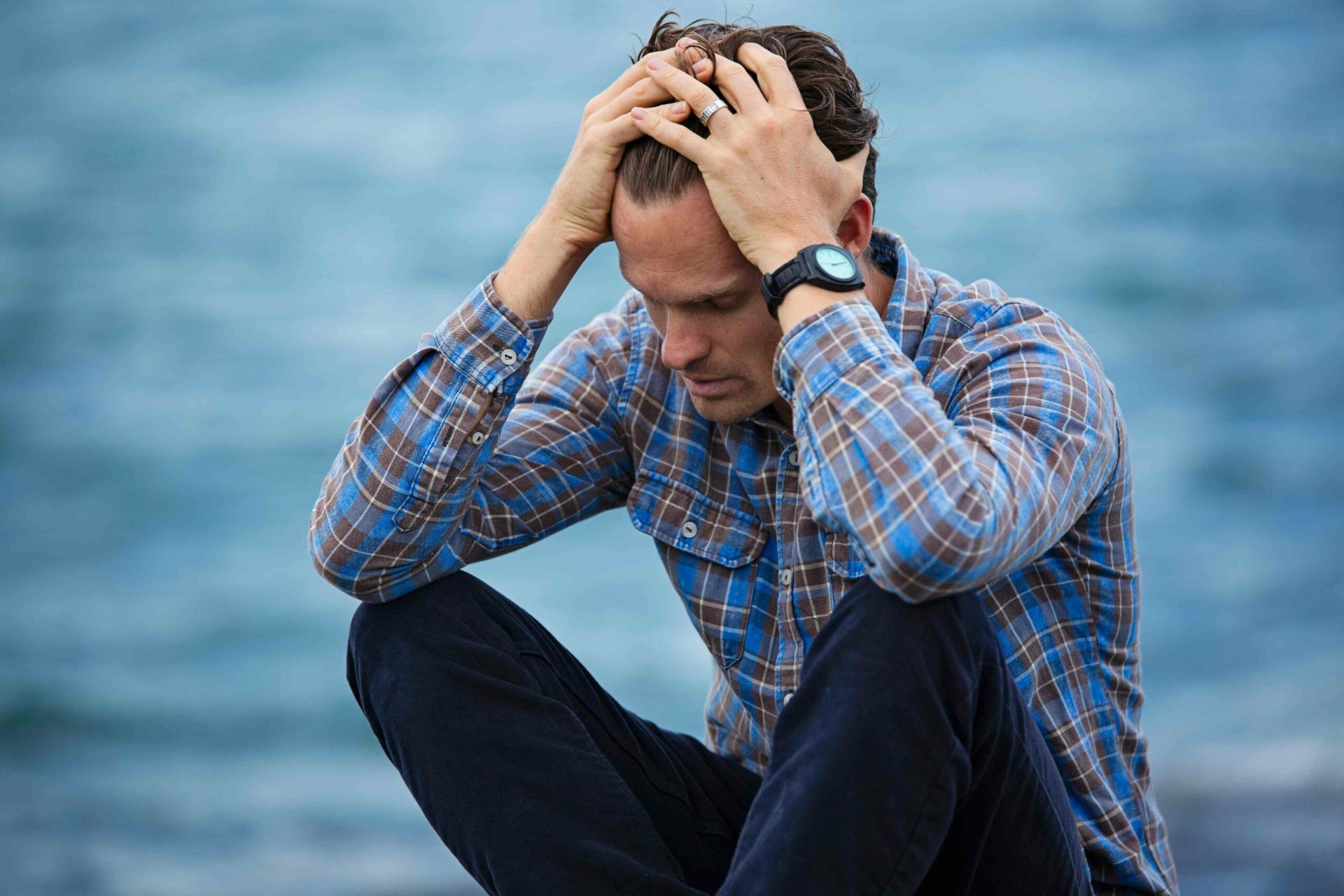 Stress, angoisses et nuits difficiles : comment retrouver l'équilibre avec le neurofeedback Homme les mains dans la tête au bord de l'eau illustrant le poids du stress et des angoisses au quotidien accompagnés par le neurofeedback dynamique NeurOptimal®